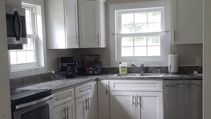 A kitchen with white cabinets, a stainless steel stove, and a window providing natural light.