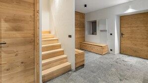 Um interior moderno com escada de madeira, um banco e uma porta.
