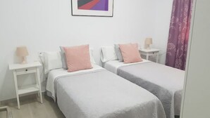 A bedroom with two single beds, white nightstands, and a framed picture on the wall. - Slaughterhouse Madrid 1 (Madrid)