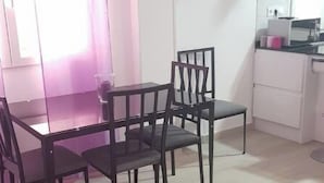 A dining area with a table and chairs, a pink armchair, and a kitchen area with a microwave. - Slaughterhouse Madrid 1 (Madrid)