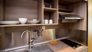 A modern kitchen with stainless steel appliances, wooden shelves, and a built-in oven. - Olea Garden Rooms (Volvi)
