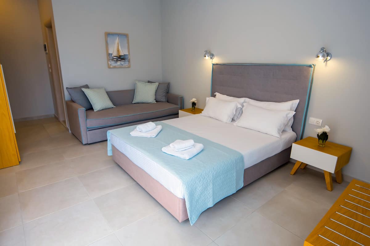 Ein Schlafzimmer mit einem Bett, einem Schlafsofa, einem Nachttisch und einer Wandlampe.