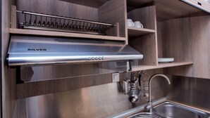 A stainless steel range hood with a control panel, a built-in wine rack, and a kitchen sink. - Olea Garden Rooms (Volvi)