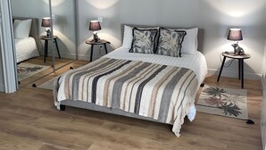 Un dormitorio con una cama grande, dos mesitas de noche con lámparas, un espejo y una obra de arte en la pared.