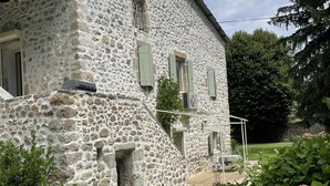 Un edificio de piedra con camino de grava y un jardín lleno de flores rosas.