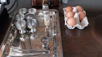 A kitchen counter with a stainless steel tray holding various utensils, a slow cooker, and a carton of eggs.