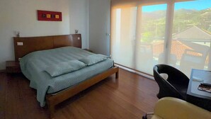 A bedroom with a bed, a chair, a table, and a view of the outside. - Hotel de Cerva (Ribeira de Pena)