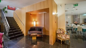 A hotel lobby with a staircase, a seating area with patterned chairs, and a reception desk. - Hotel de Cerva (Ribeira de Pena)