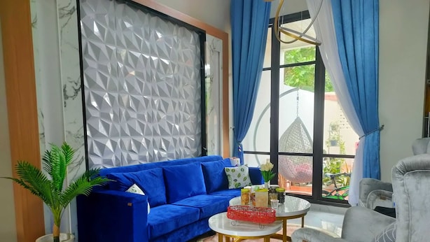 A modern living room with a blue sofa, a round coffee table, and a grey armchair. - EXPRESS O 91277 Atiq Homestay Syariah (Serang)