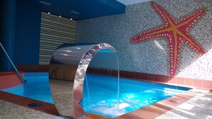 An indoor swimming pool with a water feature, tiled walls, and a starfish mural. - Amber Sea Hotel (Jurmala)