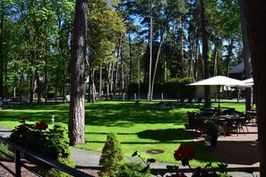 A park with a lawn, benches, and outdoor seating. - Amber Sea Hotel (Jurmala)