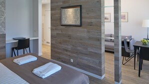 A modern hotel room with a large bed, a desk, a sofa, and a dining area. - Amber Sea Hotel (Jurmala)