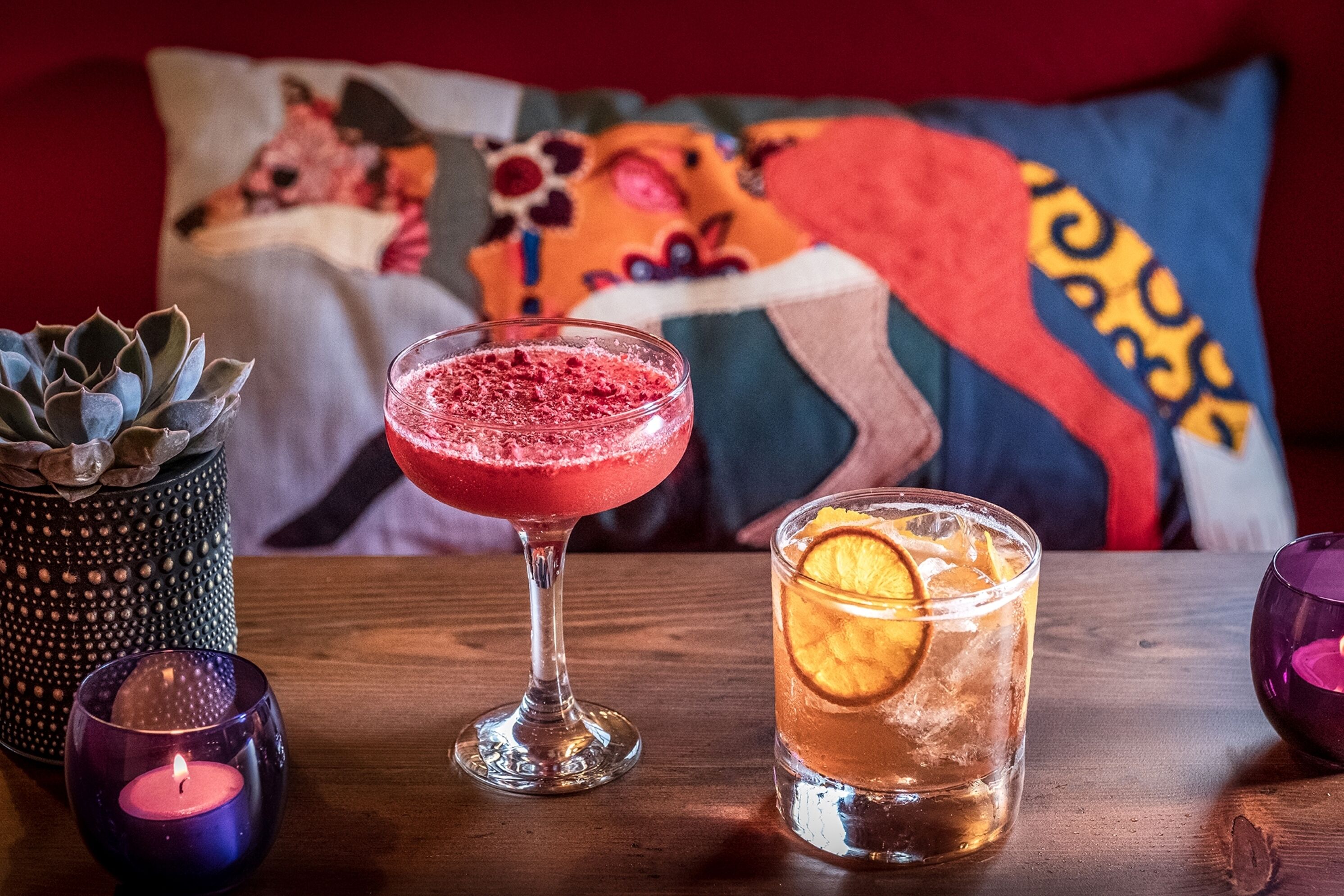 Een tafel met een drankje, een kaars en een decoratief object.