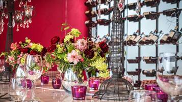 Una mesa servida con copas de vino, un llamativo centro de flores y velas moradas.