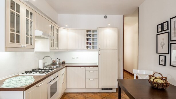 A kitchen with white cabinets, a stove, and a sink. There is a white chair and a basket on a table. - GuestHost - Apartment located on the first floor of a building without a lift (15 steps at the entrance)In 37 sqm it accommodates 4 people, with a double bedroom and a sofa bed in the living room.Tram stop under the house at 150 meters.Parking on both wh (Padova)