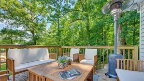 A wooden deck with outdoor furniture, a table, and a wood-burning stove. - Waterfront Sparta Home w/ Game Room & Fire Pit! (Sparta)