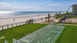 Een groene jeu-de-boulesbaan met uitzicht op het strand en de oceaan.