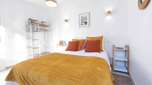 Un dormitorio con cama, armario, estante y un cuadro colgado en la pared.