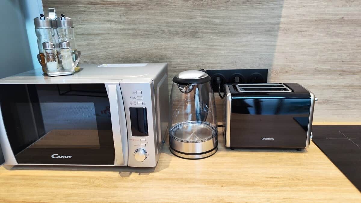 Ett kök med en mikrovågsugn, brödrost och kaffebryggare på en bänkskiva i trä.