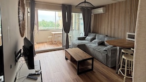 Een moderne woonkamer met een bank, salontafel en een eethoek met krukken.
