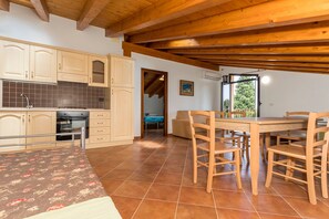 A kitchen with wooden cabinets, a dining table with chairs, and a tiled floor.