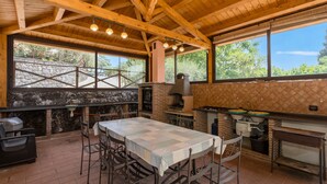 Une cuisine extérieure rustique avec un mur en pierre, des poutres en bois et un four en briques.