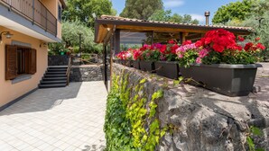 Un bâtiment doté d’un balcon, d’un espace extérieur couvert aménagé en coin salon et d’un mur en pierre orné de verdure.
