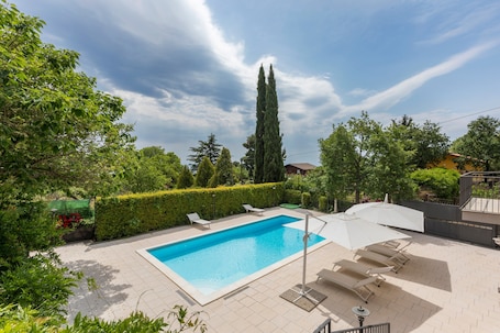 Une piscine rectangulaire, bordée d’une terrasse carrelée, entourée de verdure et d’un grand arbre.. Villa Sara sull'Etna avec piscine privée, bain à remous et Wi-Fi