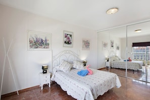 Un dormitorio con cama, dos mesitas de noche, un espejo y cuadros en la pared.