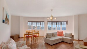 Un salón espacioso con un sofá, una mesa de comedor con sillas y ventanas amplias.