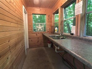Enjoy a simple kitchen with a sink, countertop, and wall-mounted fan, offering a view of the surrounding greenery.