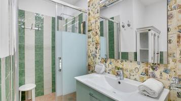 Un baño con ducha, inodoro, lavamanos y espejo.