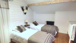 A bedroom with two beds, a headboard, a lamp, and a mounted animal head.