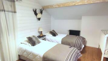 Een slaapkamer met twee bedden, een hoofdbord, een lamp en een opgehangen dierenhoofd.