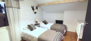 Un dormitorio con dos camas, cabeceros, una lámpara y una cabeza de animal montada.