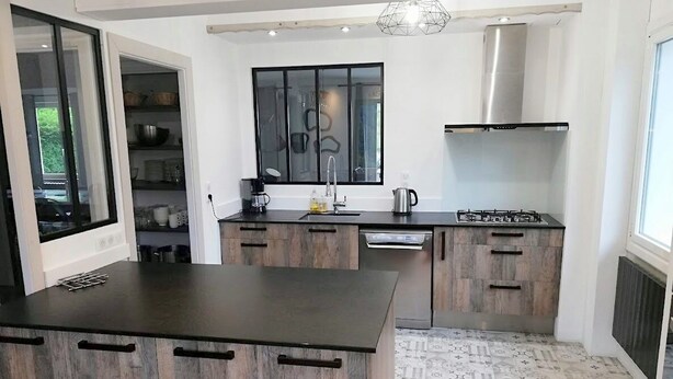 A modern kitchen with a central island, built-in cabinets, and a stainless steel range hood.
