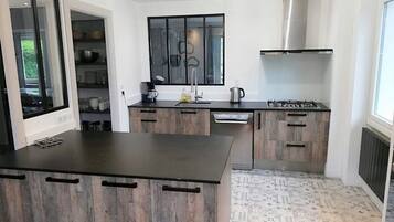 Een moderne keuken met een centraal eiland, inbouwkastjes en een roestvrijstalen afzuigkap.