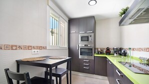 A kitchen with a dining table, chairs, a microwave, oven, and a green countertop. - Pet-Friendly Piso Arquillo del Reloj Apartment with Wi-Fi (Chiclana de la frontera)