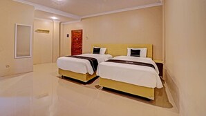 A hotel room with two beds, a mirror, a door, and a light fixture. - Super OYO Collection O Andono Hotel (Temon)