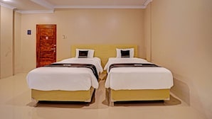 A hotel room with two beds, a wooden door, and a light-colored wall. - Super OYO Collection O Andono Hotel (Temon)