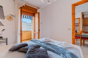 A bedroom with a bed, a desk, a chair, and a dining area with a table and chairs.
