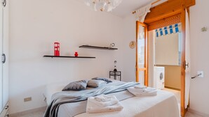 Ein Schlafzimmer mit Bett, Waschmaschine und einer Tür zu einem weiteren Raum.