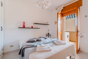 Une chambre à coucher avec un lit, un lave-linge et une porte donnant sur une autre pièce.