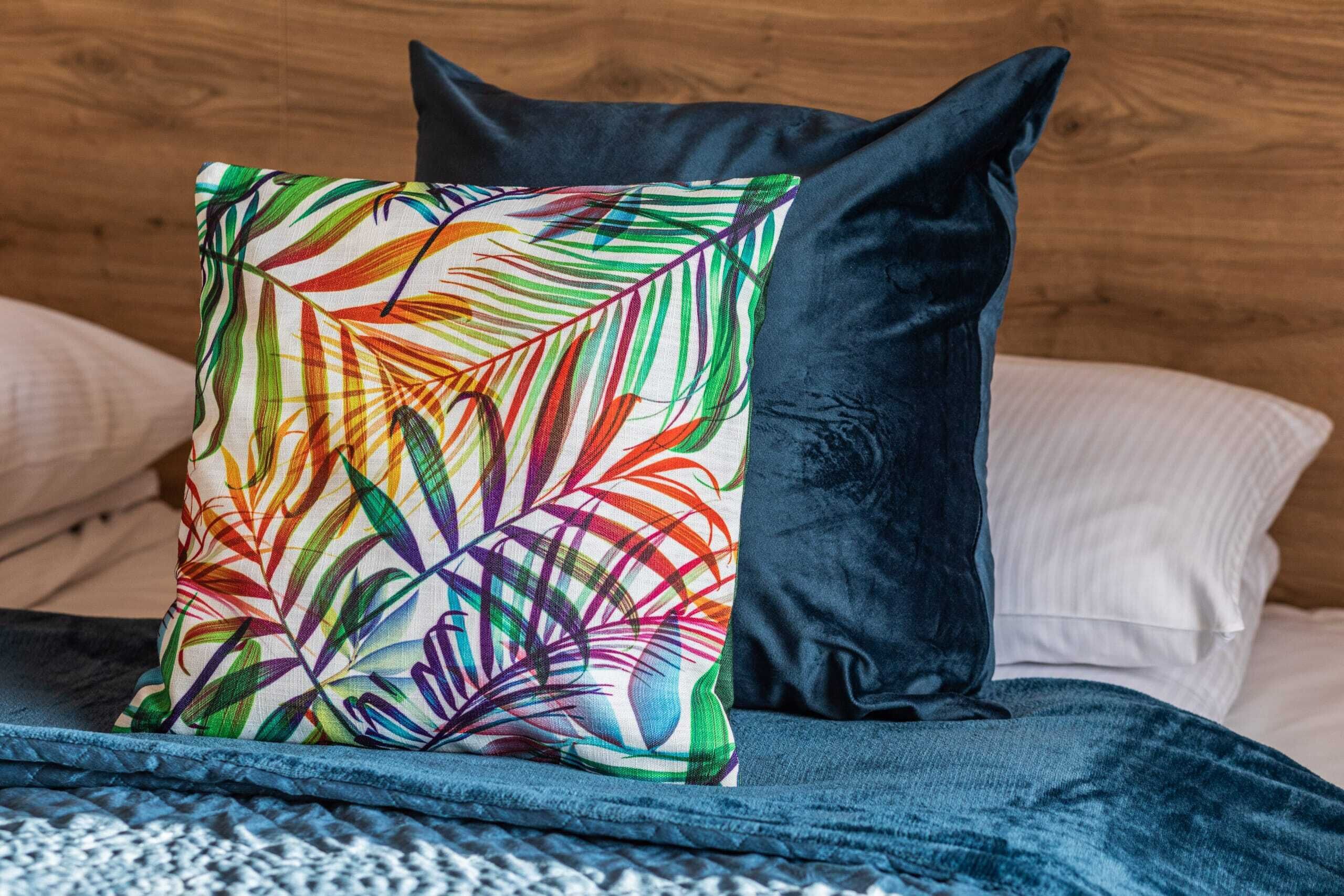 A bed with a colorful pillow, a dark pillow, and a wooden headboard.