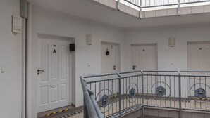 Un edificio de varios pisos con puertas blancas numeradas 18, 20 y 10, y una barandilla metálica en el centro.