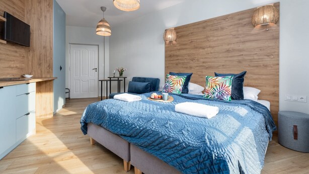 Un dormitorio moderno con una cama grande, detalles de madera, un escritorio y un televisor.