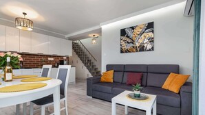Un salon moderne avec un canapé gris, une table basse blanche et un coin repas comprenant une table et des chaises blanches.