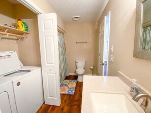 Une petite salle de bain équipée d’un lave-linge, de toilettes et d’un lavabo.