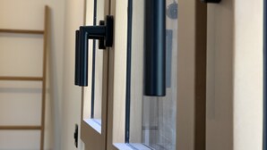 Una finestra con una maniglia nera e una scala di legno appoggiata al muro.
