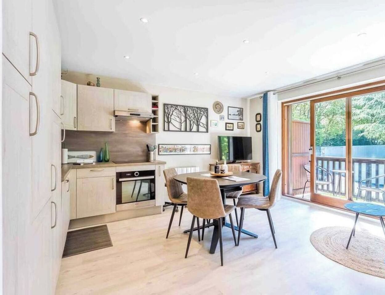 Una cocina moderna con armarios de madera y un comedor con una mesa redonda y sillas.